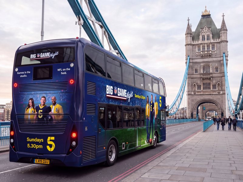 Channel 5 Big Game Night bus wrap on Tower Bridge, London, showing the side and rear of a double-decker with the three presenters in yellow jackets on a stadium background
