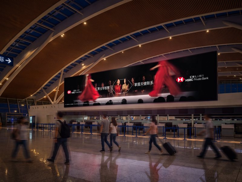 HSBC Private Bank Chinese-language large-format advert above the check-in desks at Shanghai airport, with travellers walking through the terminal below