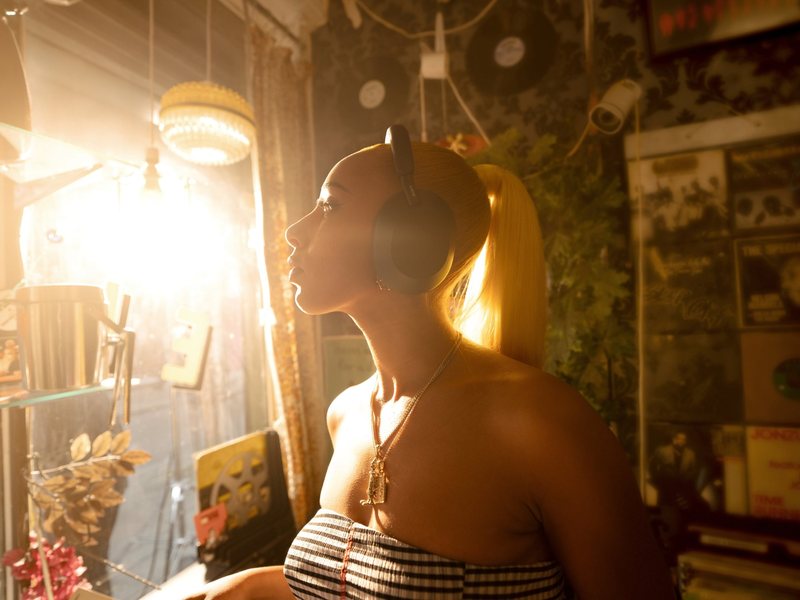 Sony headphones campaign: a woman in black Sony headphones in a sunlit vintage record shop, in profile against the window light